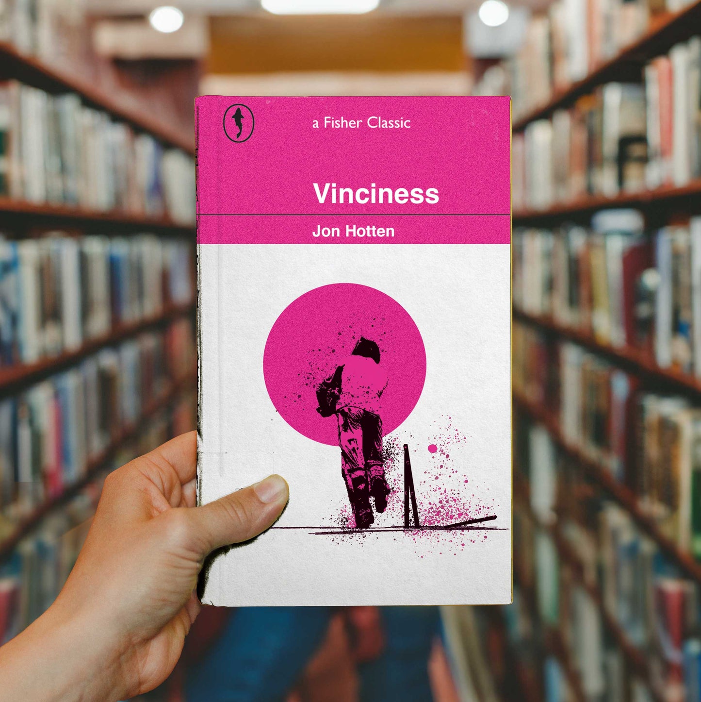 Hand holding Vinciness paperback edition mockup in a library setting